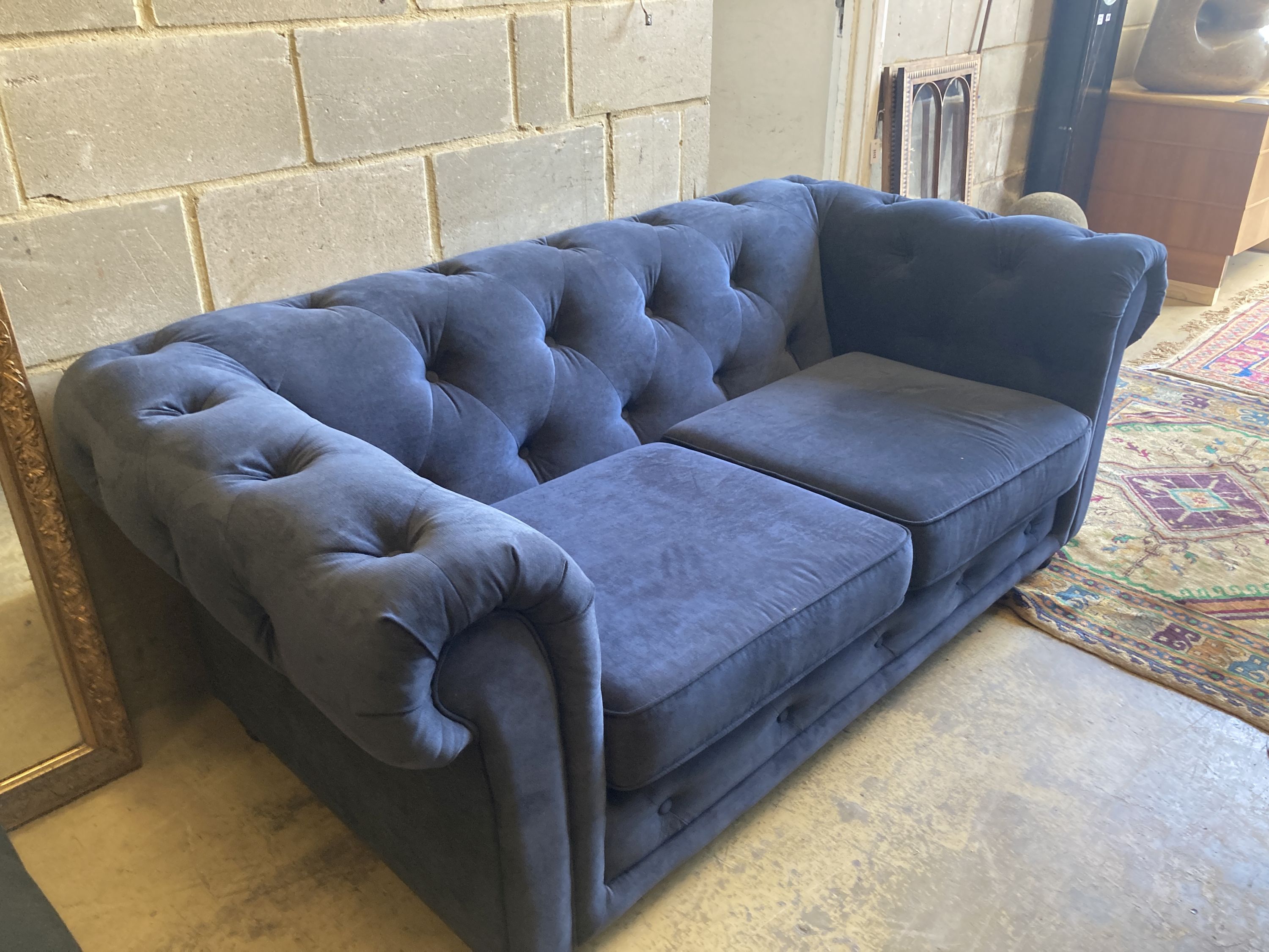 A pair of Chesterfield style settees upholstered in blue dralon and a footstool, largest length 210cm, depth 96cm, height 74cm